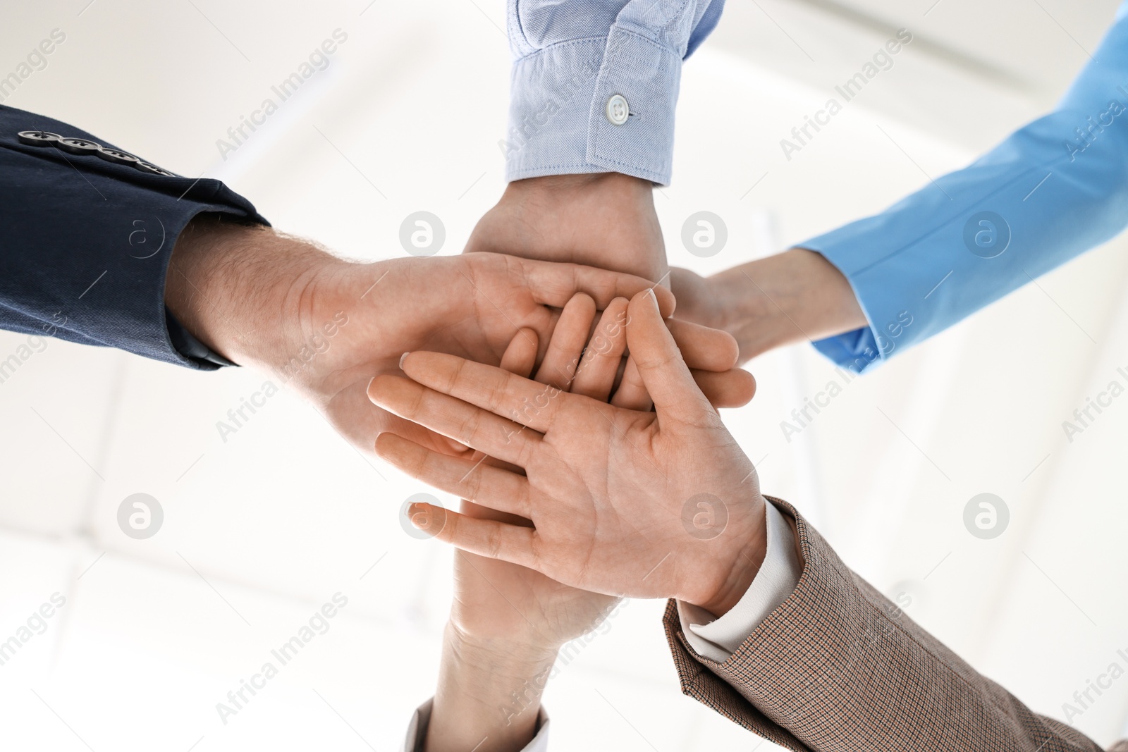 Photo of Teamwork. Group of people joining hands together indoors, bottom view