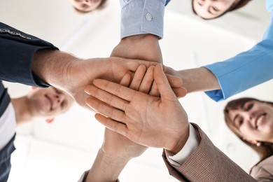 Teamwork. Group of people joining hands together indoors, bottom view