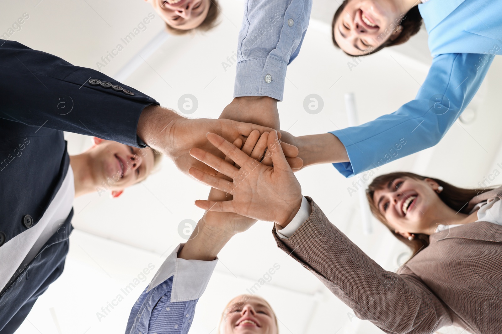 Photo of Teamwork. Group of people joining hands together indoors, bottom view