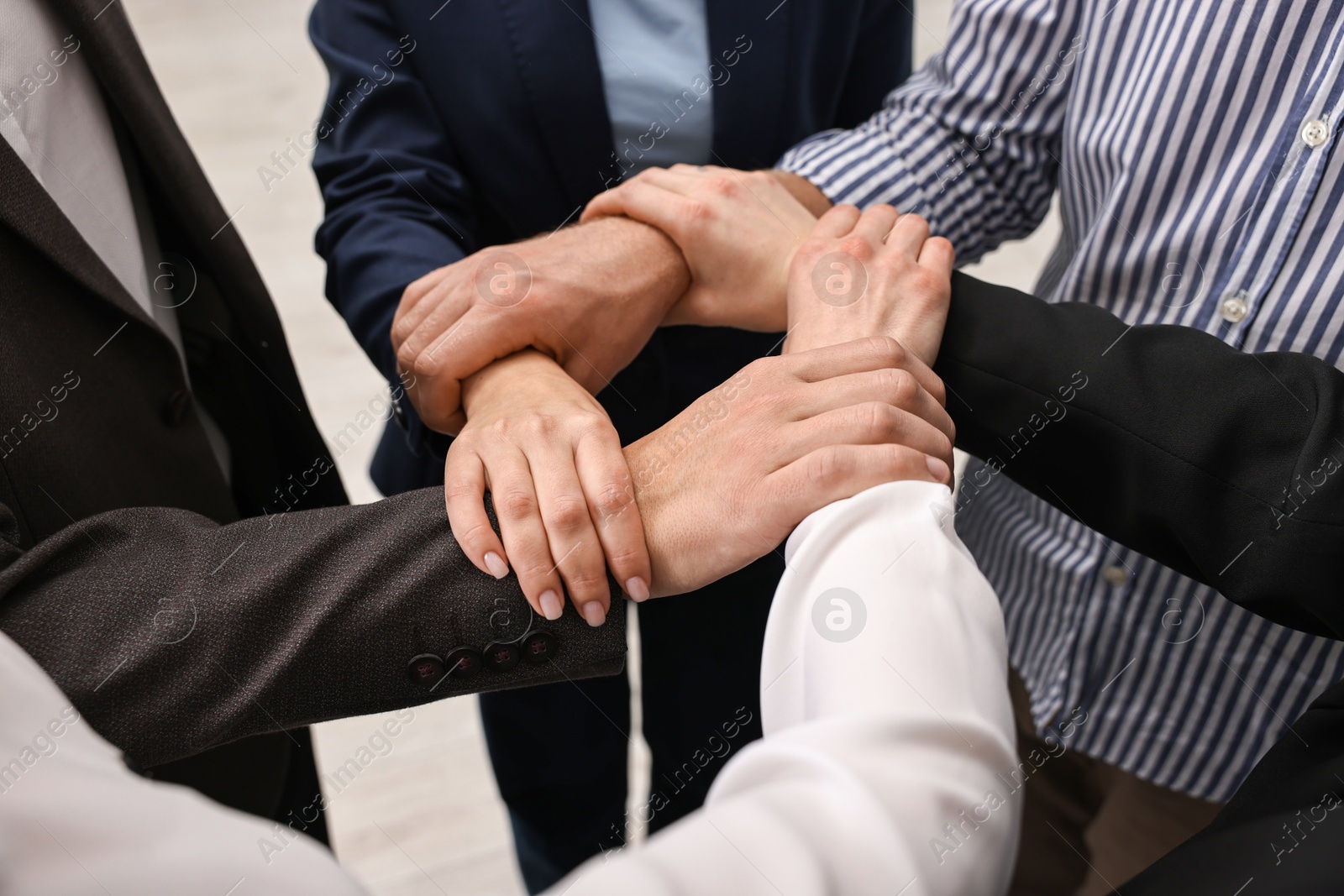 Photo of Teamwork. Group of people holding hands together indoors, closeup