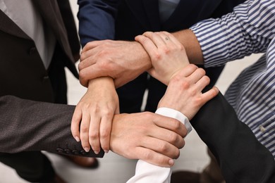 Teamwork. Group of people holding hands together indoors, closeup