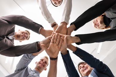 Photo of Teamwork. Group of people joining hands together indoors, bottom view