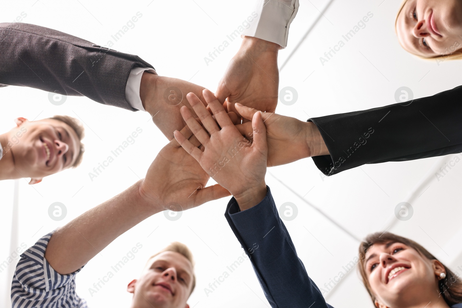 Photo of Teamwork. Group of people joining hands together indoors, bottom view