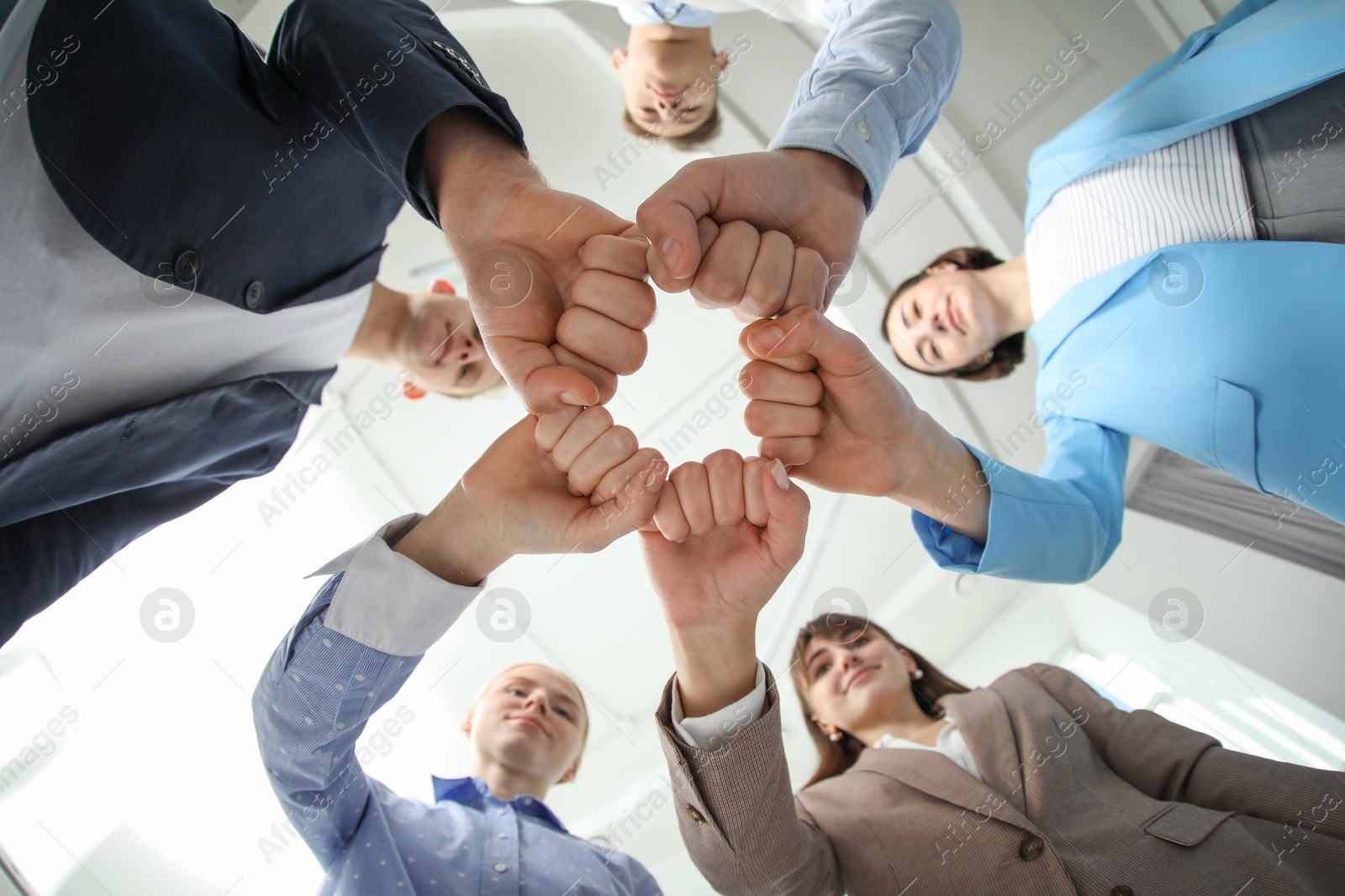 Photo of Teamwork. Group of people joining fists together indoors, bottom view