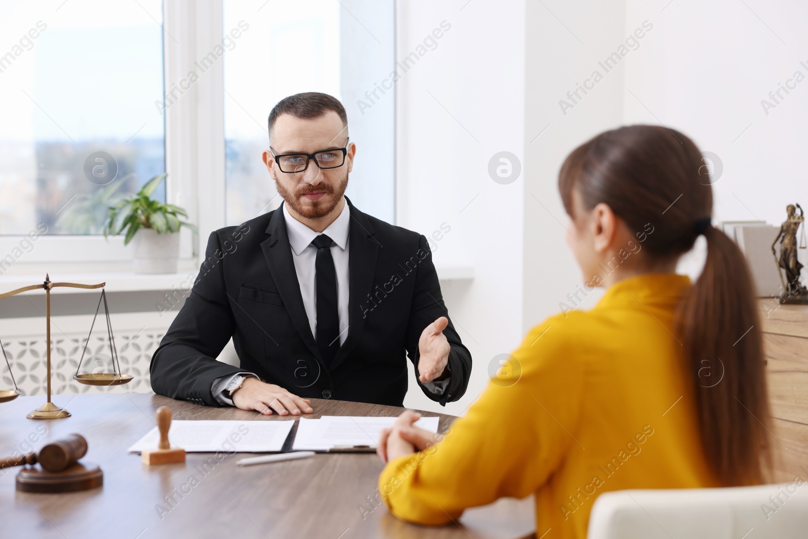 Photo of Woman having meeting with professional lawyer at wooden desk indoors