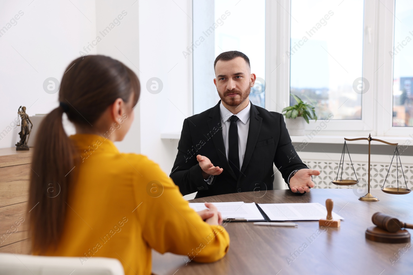 Photo of Woman having meeting with professional lawyer at wooden desk indoors