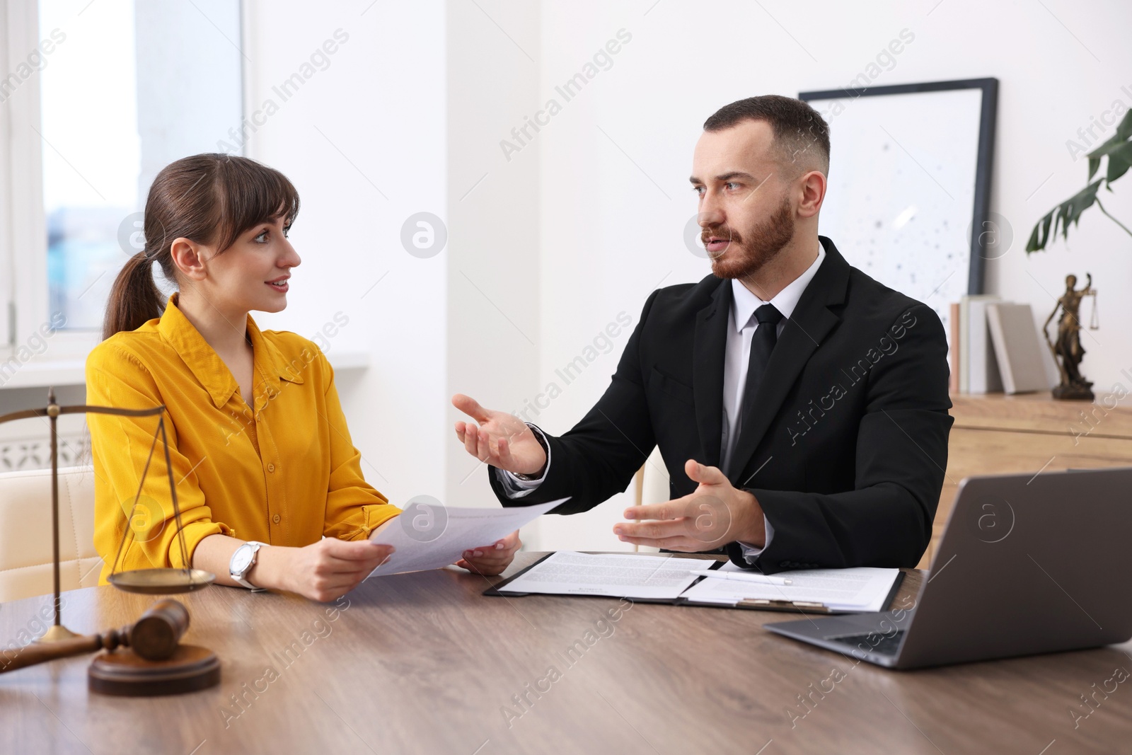 Photo of Woman having meeting with professional lawyer at wooden desk indoors