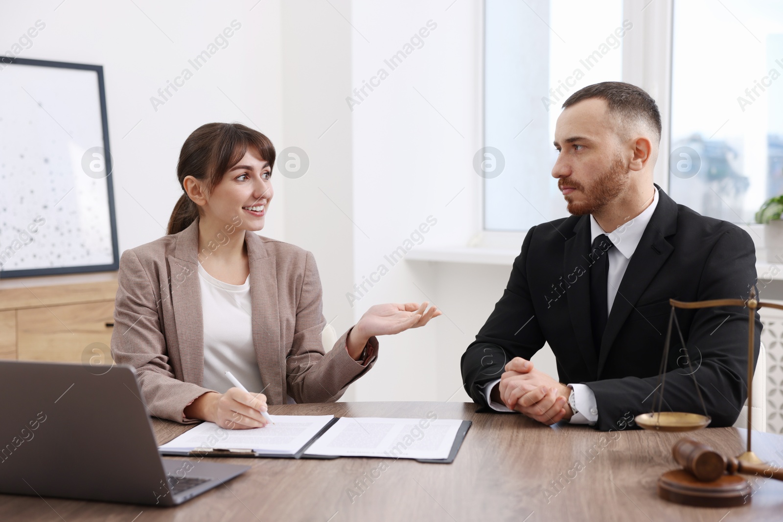 Photo of Client signing notarial paperwork during meeting with lawyer at wooden desk indoors