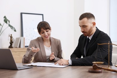 Man having meeting with professional notary at wooden desk indoors