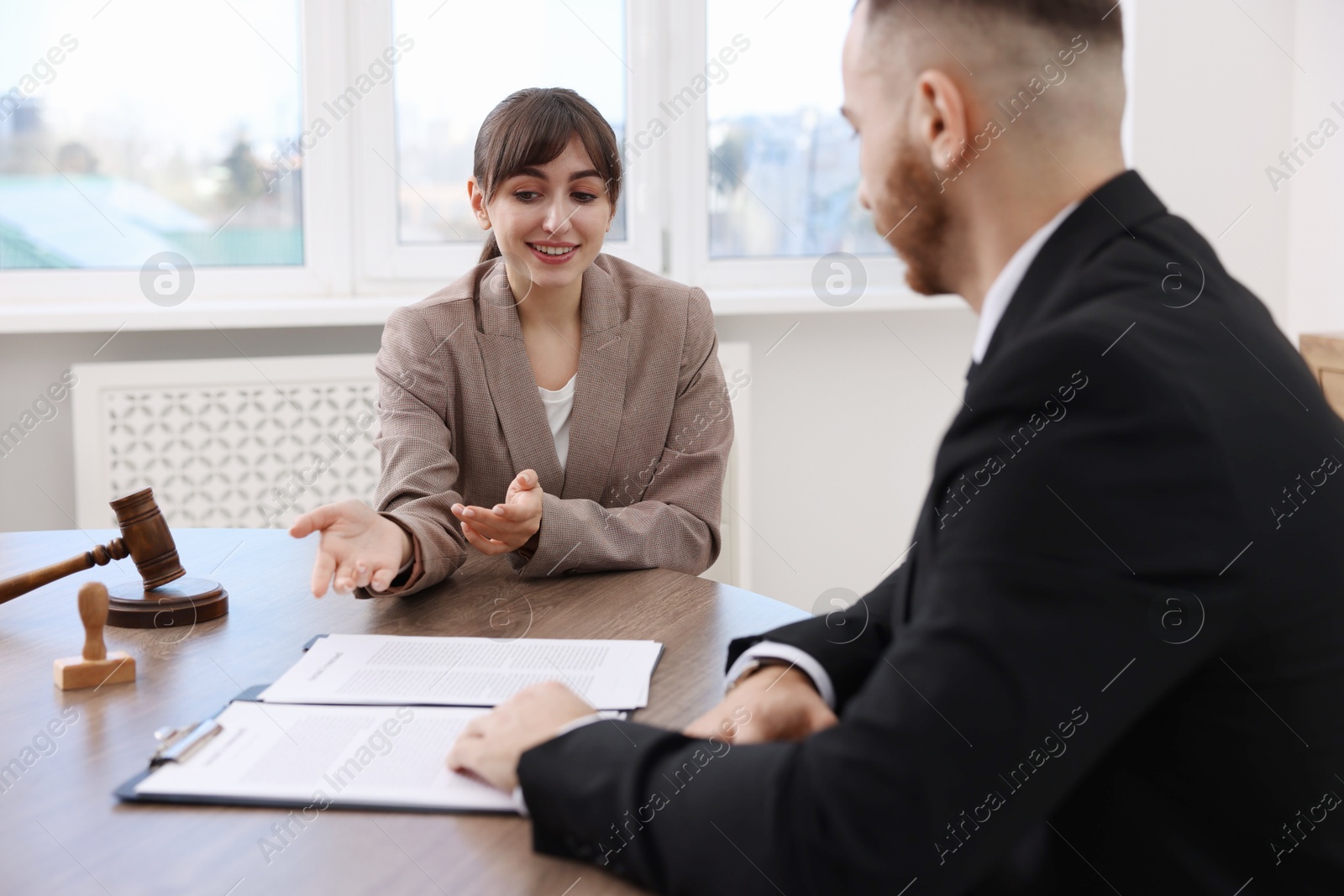 Photo of Man having meeting with professional notary at wooden desk indoors