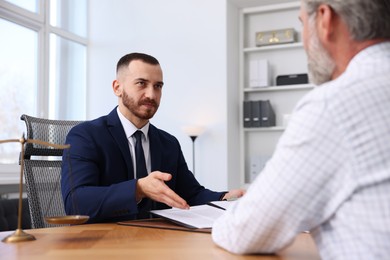 Photo of Man having meeting with professional notary at wooden desk indoors