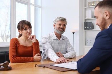 Couple having meeting with professional notary at wooden desk indoors