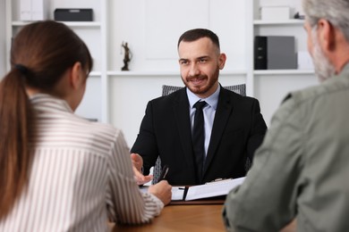 Photo of Man and woman having meeting with professional lawyer at wooden desk indoors