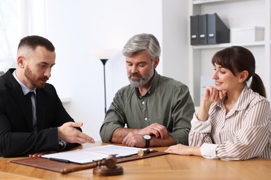 Couple having meeting with professional lawyer at wooden desk indoors