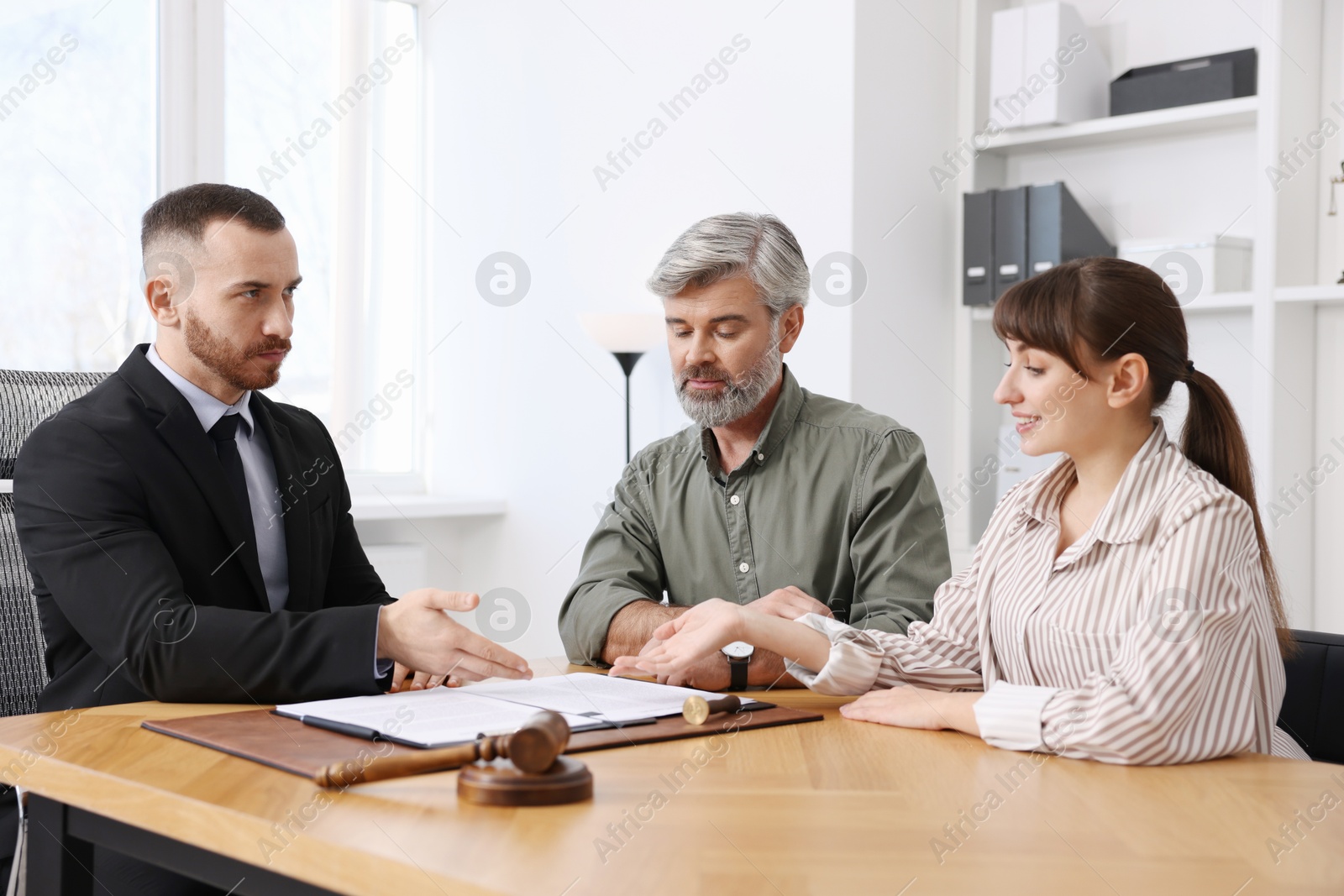 Photo of Couple having meeting with professional lawyer at wooden desk indoors