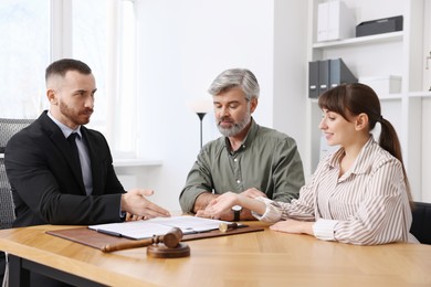 Couple having meeting with professional lawyer at wooden desk indoors