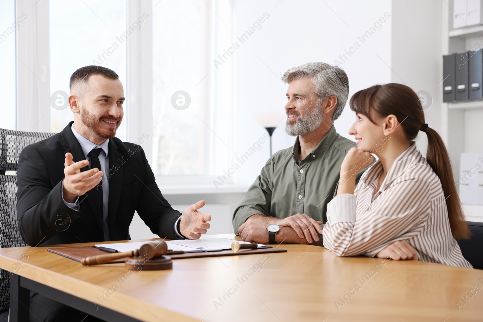 Photo of Couple having meeting with professional lawyer at wooden desk indoors