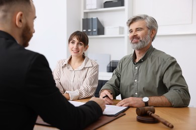 Photo of Couple having meeting with professional lawyer at wooden desk indoors