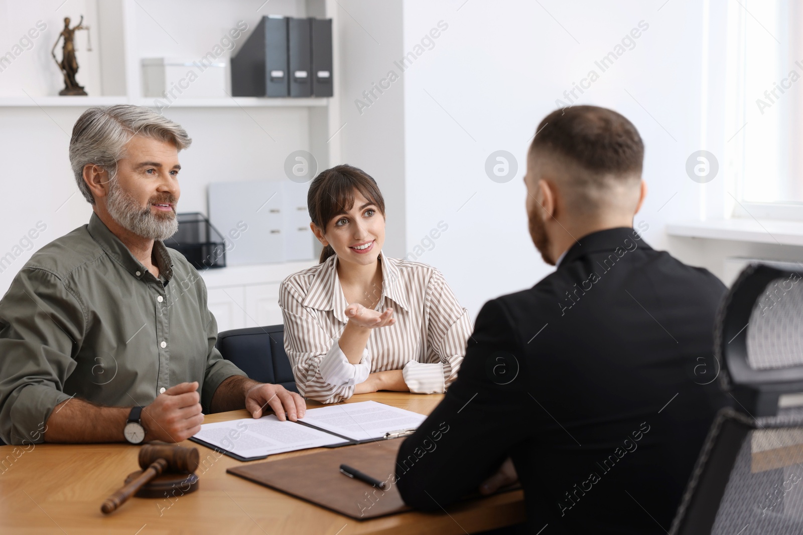 Photo of Couple having meeting with professional lawyer at wooden desk indoors