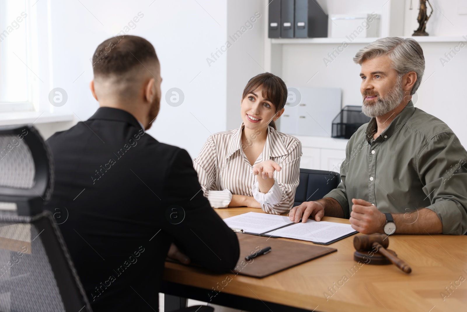 Photo of Couple having meeting with professional lawyer at wooden desk indoors