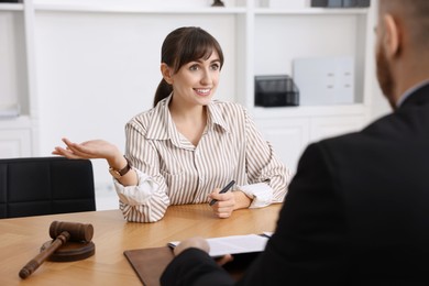 Photo of Woman having meeting with professional notary at wooden desk indoors