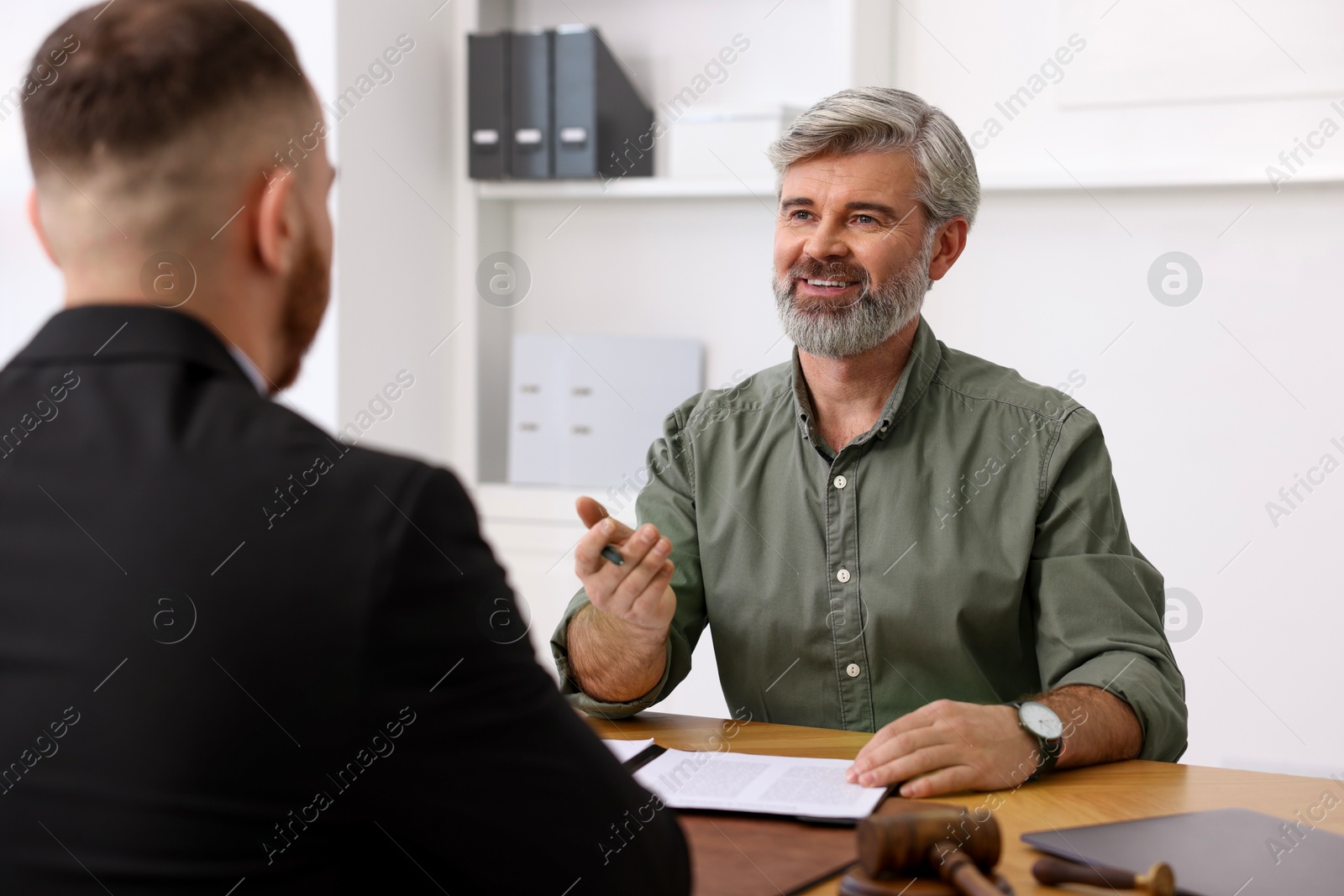 Photo of Man having meeting with professional lawyer at wooden desk indoors