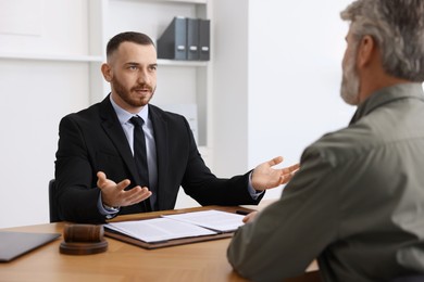 Photo of Man having meeting with professional lawyer at wooden desk indoors