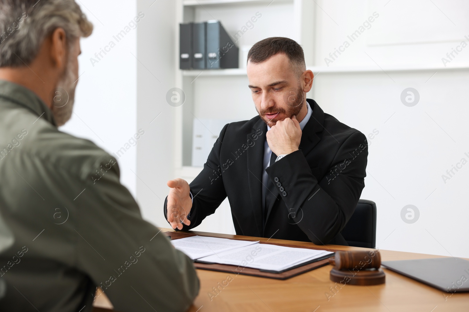 Photo of Man having meeting with professional lawyer at wooden desk indoors