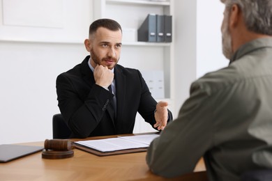 Photo of Man having meeting with professional lawyer at wooden desk indoors