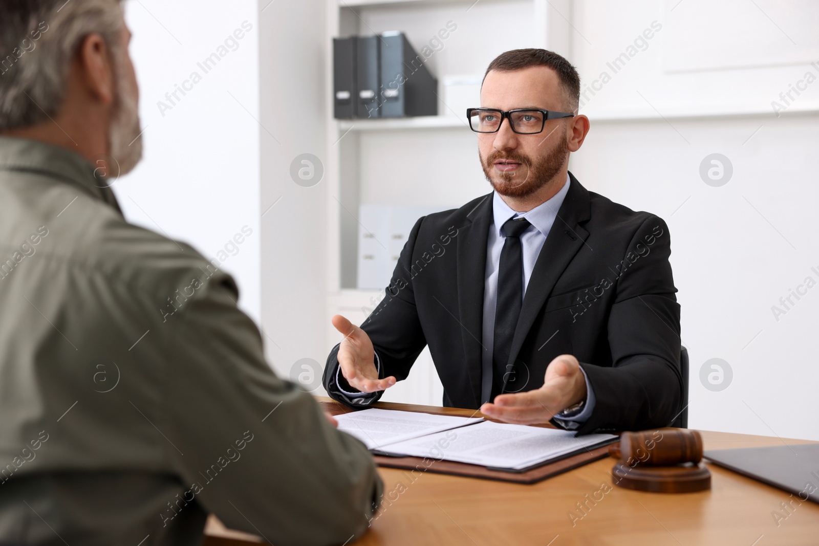 Photo of Man having meeting with professional lawyer at wooden desk indoors