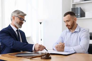 Man having meeting with professional lawyer at wooden desk indoors