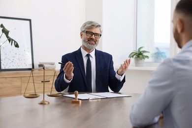 Photo of Man having meeting with professional lawyer at wooden desk indoors