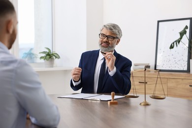 Man having meeting with professional lawyer at wooden desk indoors