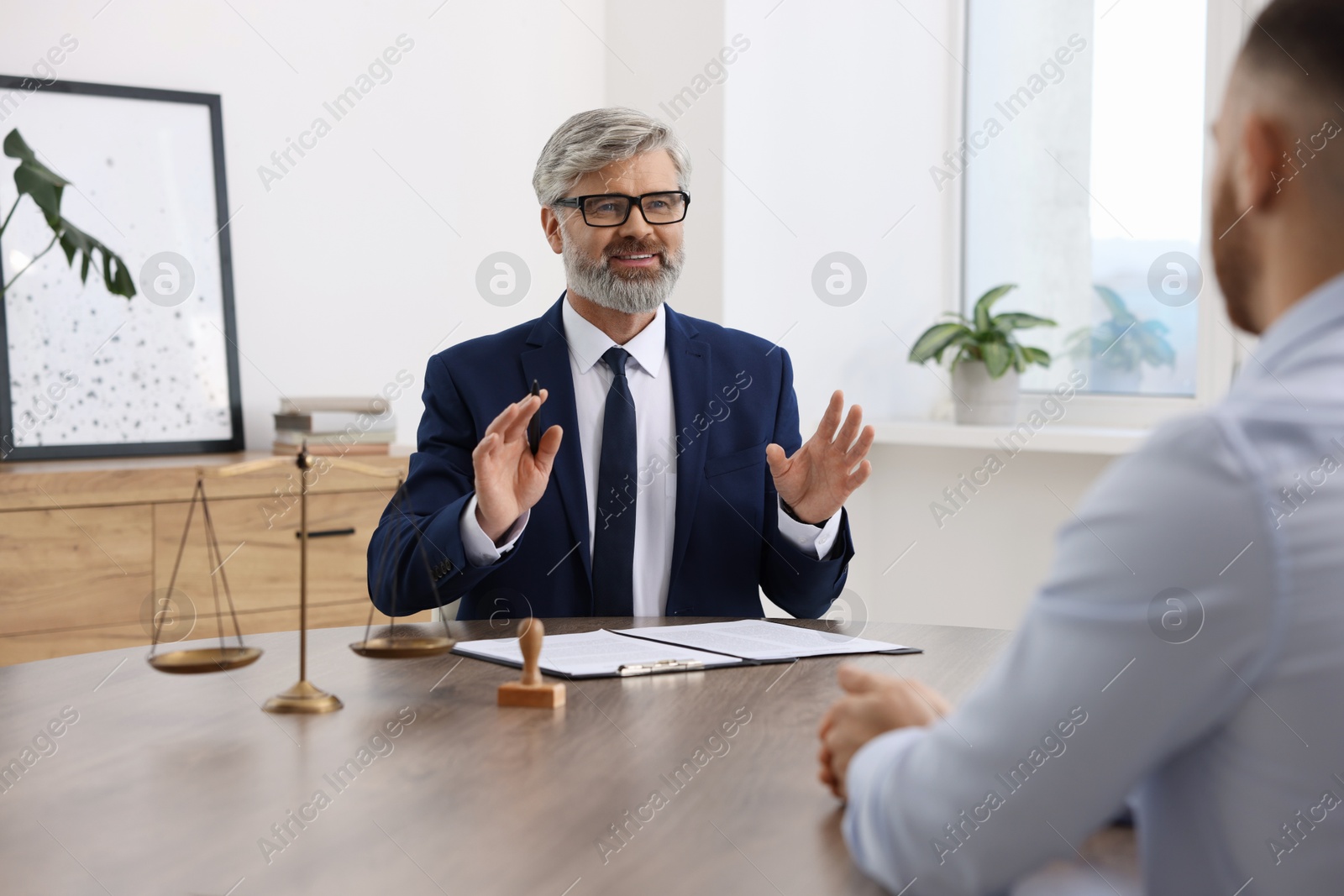 Photo of Man having meeting with professional lawyer at wooden desk indoors