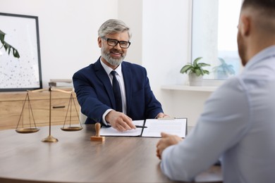 Photo of Man having meeting with professional lawyer at wooden desk indoors