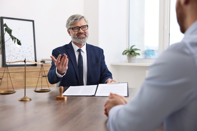 Photo of Man having meeting with professional lawyer at wooden desk indoors