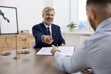 Client signing notarial paperwork during meeting with lawyer at wooden desk indoors