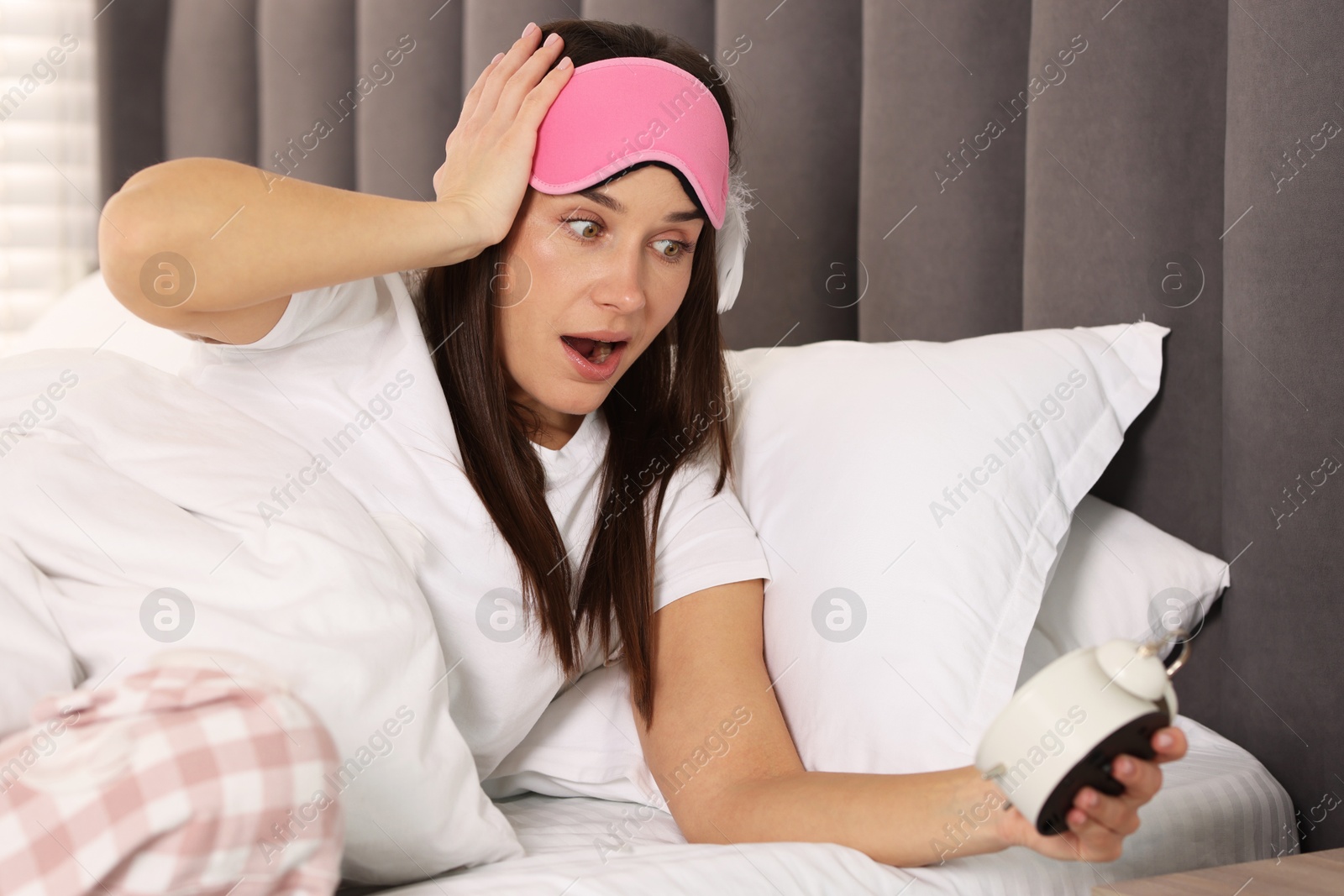 Photo of Overslept woman with alarm clock in bed at home