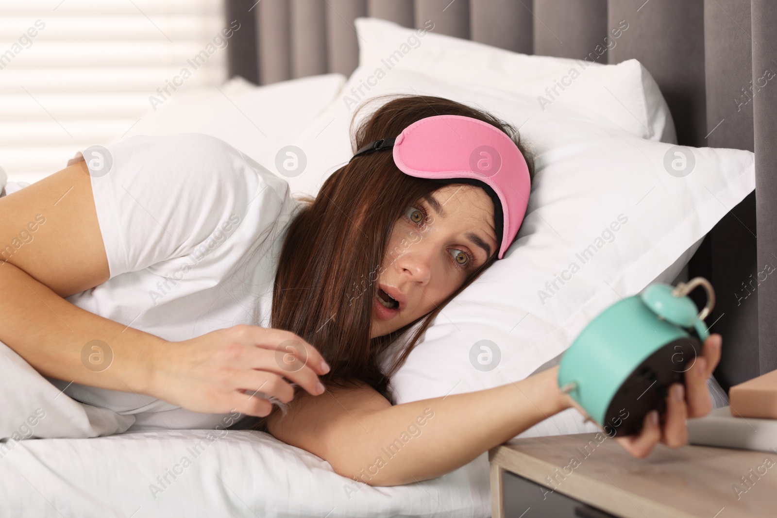 Photo of Overslept woman with alarm clock in bed at home