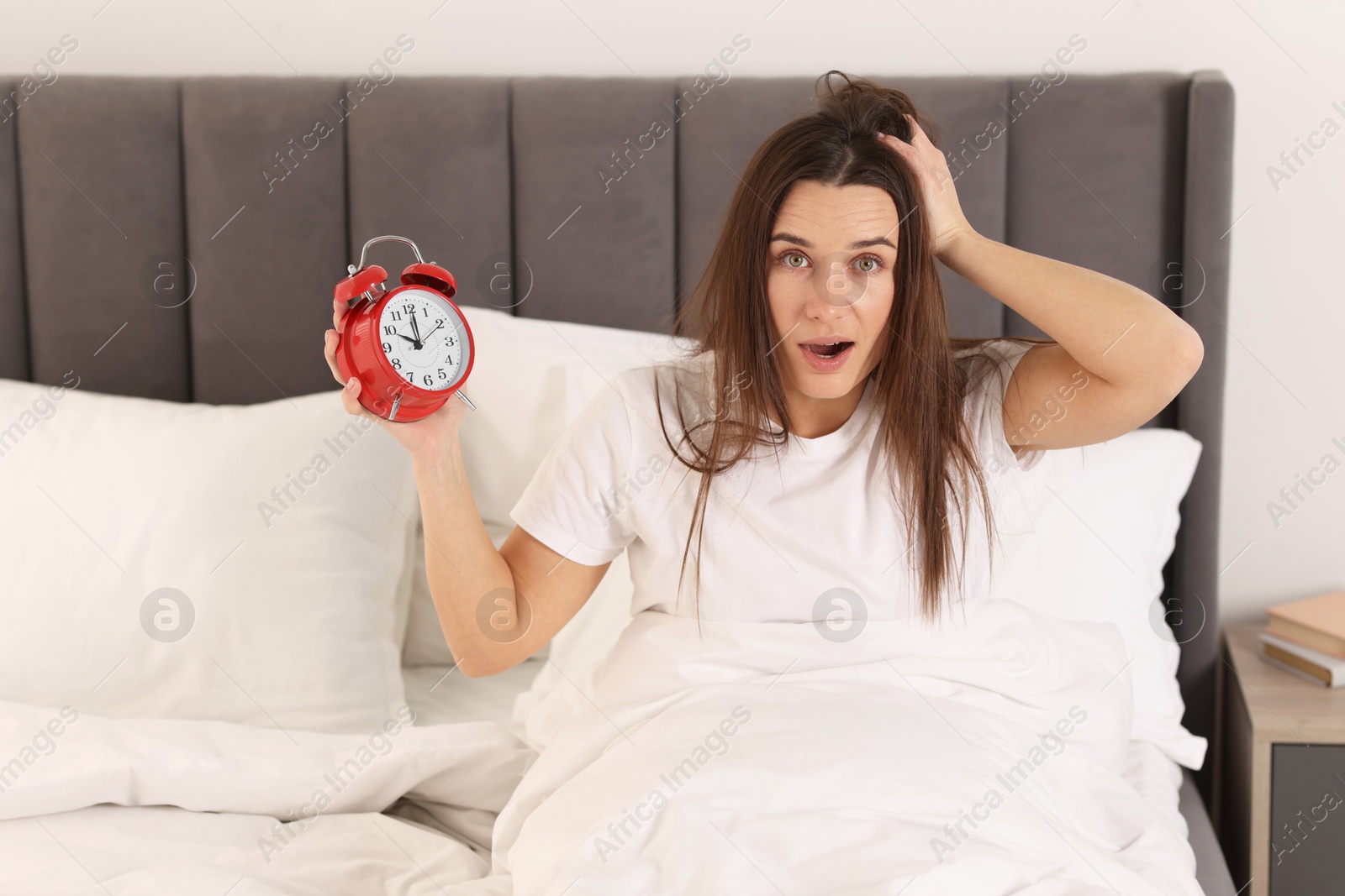 Photo of Overslept woman with alarm clock in bed at home