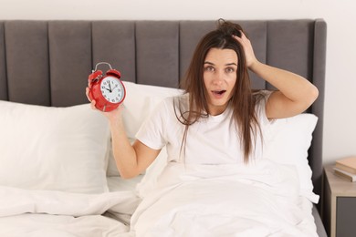 Overslept woman with alarm clock in bed at home