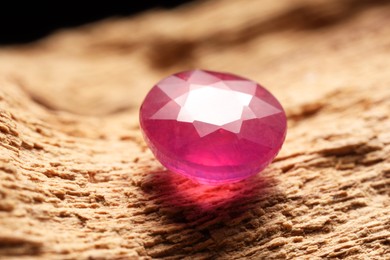 Photo of Beautiful shiny pink gemstone on stone, closeup