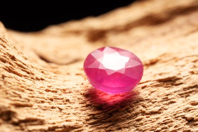 Photo of Beautiful shiny pink gemstone on stone, closeup