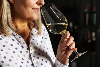 Photo of Professional sommelier tasting white wine indoors, closeup