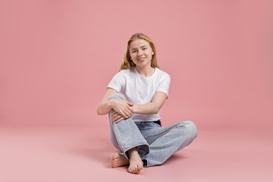 Smiling woman in stylish jeans on pink background