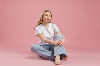 Photo of Beautiful young woman in stylish jeans on pink background