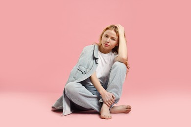 Beautiful young woman in stylish jeans on pink background