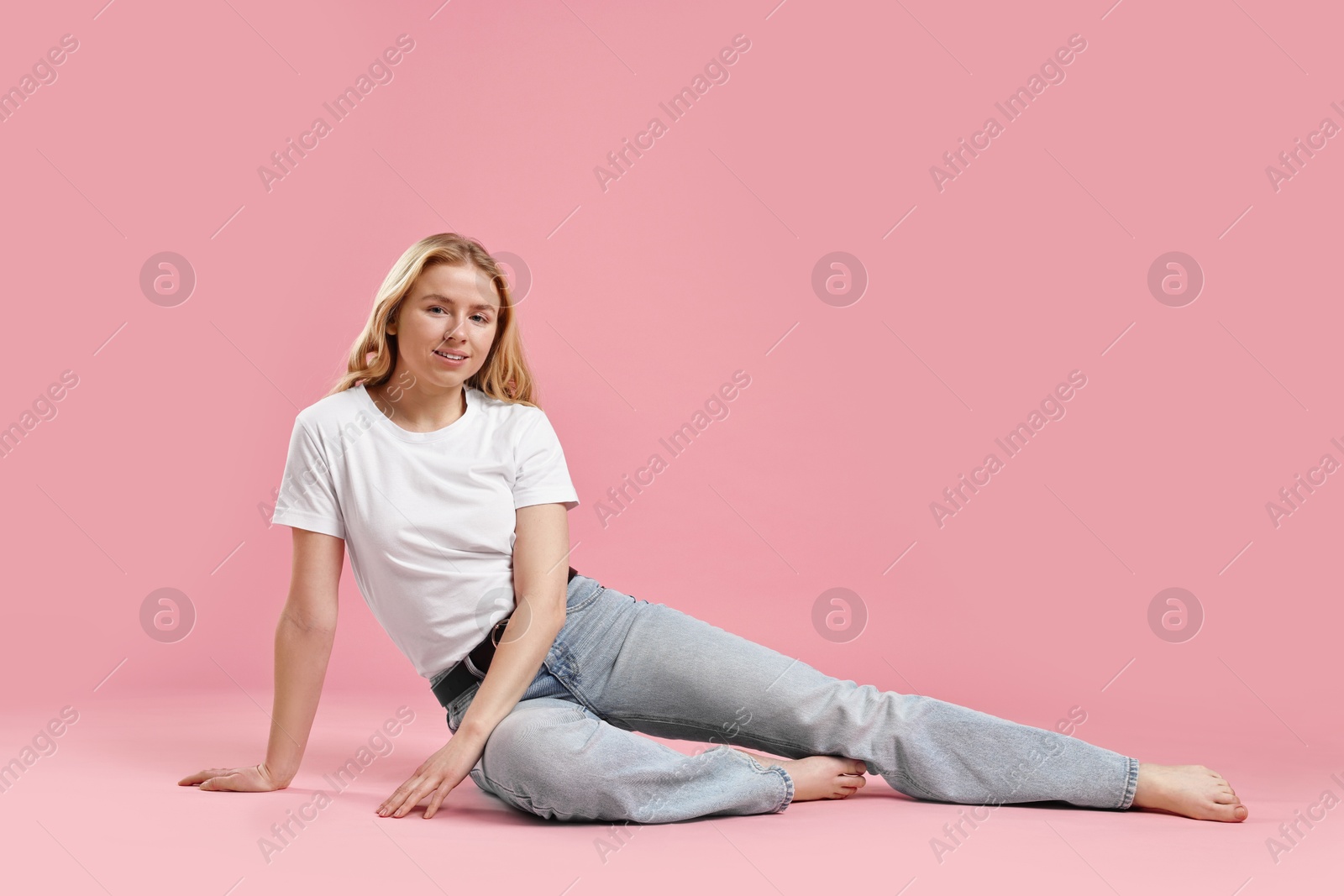 Photo of Smiling woman in stylish jeans on pink background. Space for text