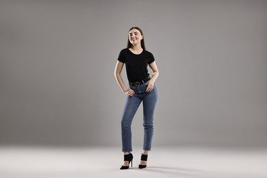 Photo of Smiling woman in stylish jeans on grey background