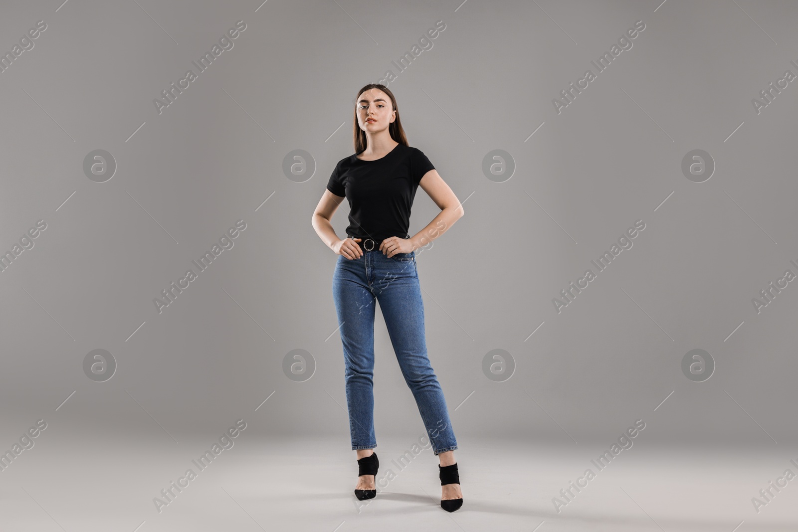 Photo of Beautiful young woman in stylish jeans on grey background